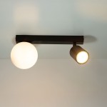 Czarna lampa sufitowa Tavira z dwoma źródłami światła: okrągła kula z białego szkła oraz reflektor w formie cylindra. Ujęcie z góry, lampa zamontowana na suficie, prezentuje nowoczesny design.