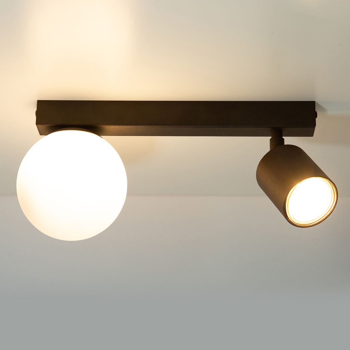 Lampa sufitowa Tavira w kolorze brązowym, z okrągłym kloszem z białego szkła i regulowanym reflektorem. Produkt zamontowany na prostokątnej podstawie, ukazujący nowoczesny design. Widok z boku, na jasnym tle.