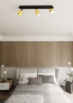 Czarna lampa sufitowa 3-punktowa Zen z żółtymi kloszami, zamontowana na drewnianym suficie, skierowana w dół. Lampa znajduje się nad łóżkiem z szarymi poduszkami, w nowoczesnej sypialni z jasnym tłem.