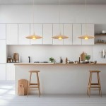 Lampa wisząca Astra 1xE27 w kolorze sabbia, o okrągłym kloszu, zawieszona nad drewnianym blatem w nowoczesnej kuchni. Widoczne trzy lampy w równej odległości, z żarówkami w środku, na tle białych mebli i drewnianych akcesoriów.