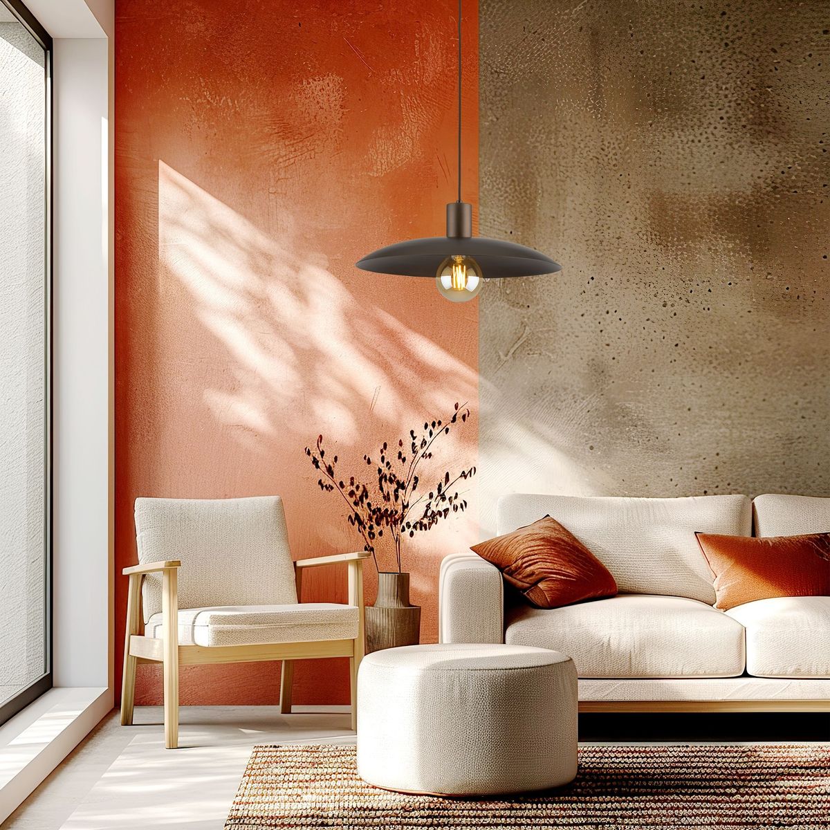 Lampa wisząca Astra w kolorze brązowym, z pojedynczym gniazdem E27, zawieszona nad sofą w jasnym wnętrzu. W tle widoczna ściana w odcieniach pomarańczowego i szarego, z naturalnym światłem wpadającym przez okno.