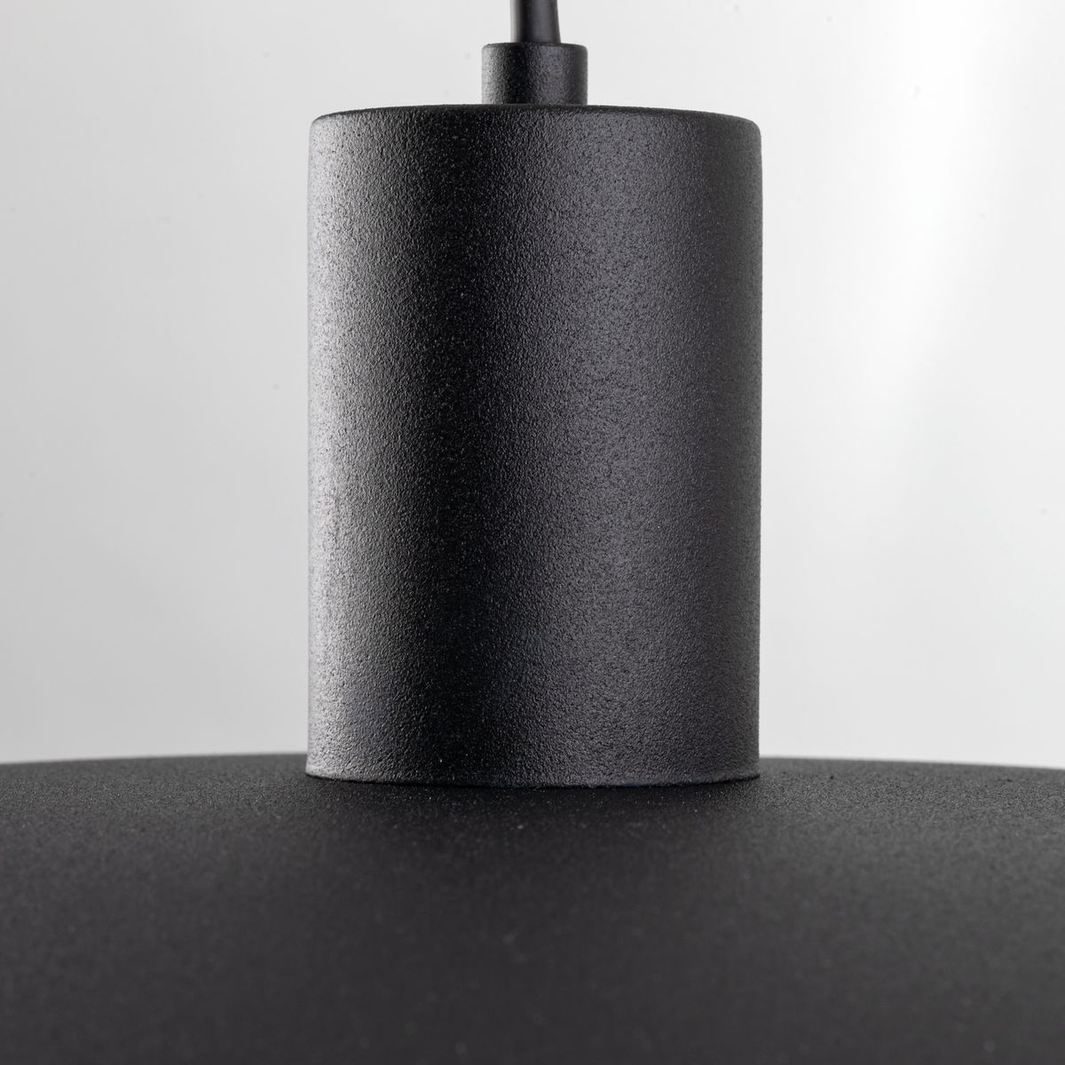 Czarna lampa wisząca Astra z mocowaniem E27, widok z bliska na górną część lampy. Materiał matowy, cylindryczny kształt, prosty design bez zdobień.