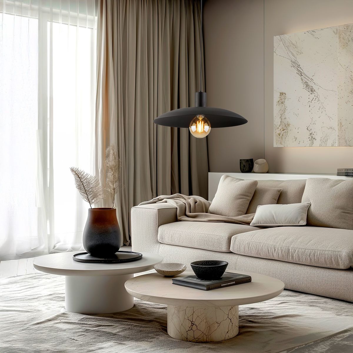 Czarna lampa wisząca Astra z oprawą na żarówkę E27, zawieszona nad okrągłym stolikiem. W tle widoczna kanapa w jasnych odcieniach oraz dekoracje, takie jak wazon z roślinami i książki. Pomieszczenie o stonowanej kolorystyce, z dużymi oknami.