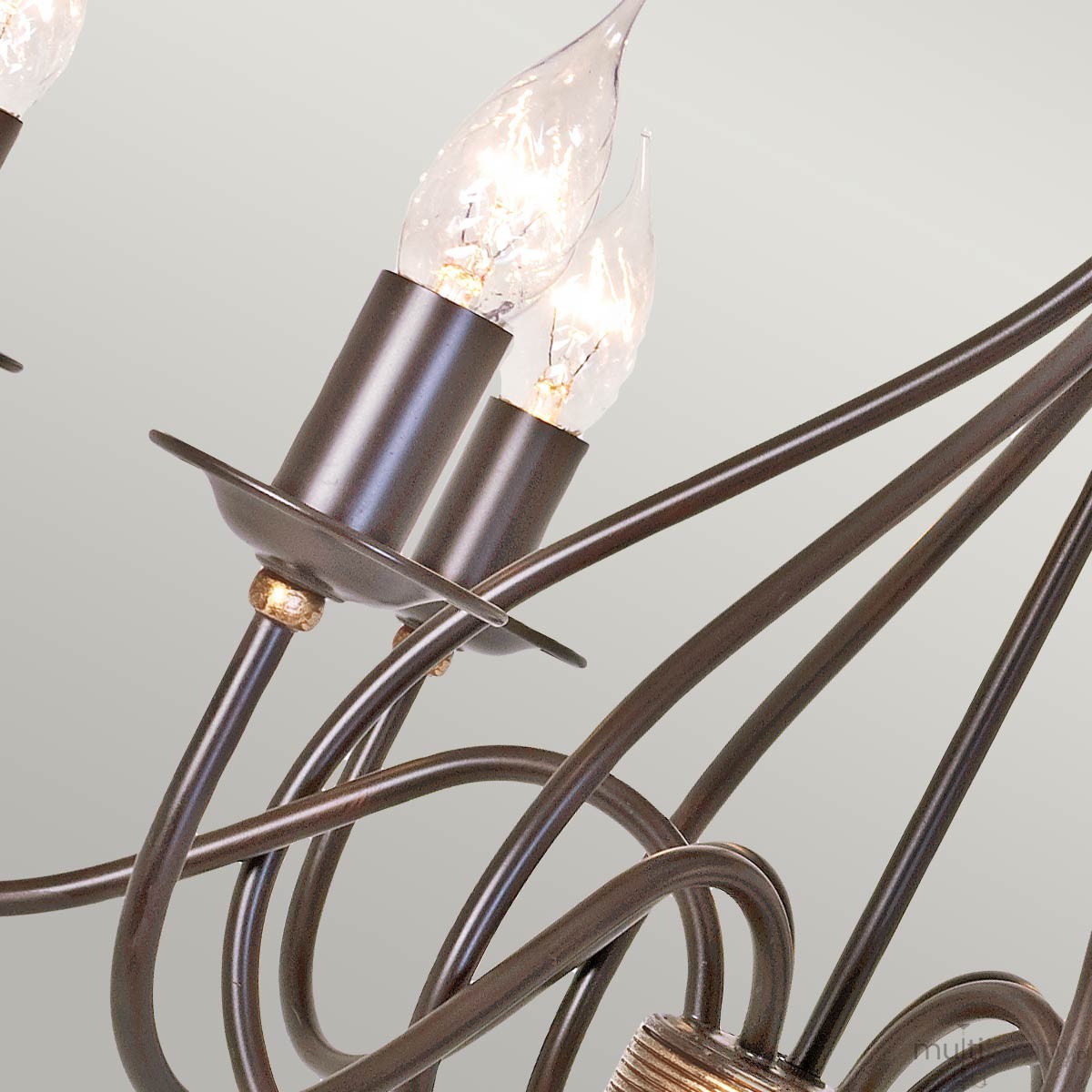 Lampa wisząca Windermere w kolorze złoto-brązowym z sześcioma miejscami na żarówki E14. Widoczne zakrzywione ramiona oraz eleganckie, przezroczyste klosze w kształcie łezki. Ujęcie z boku, ukazujące detale konstrukcji.