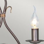 Kinkiet Windermere w kolorze złoto-brązowym, z dwoma gniazdami E14. Widoczna jest elegancka, przezroczysta żarówka w kształcie łzy oraz metalowa podstawa z dekoracyjnymi detalami. Kąt ujęcia ukazuje elementy konstrukcyjne kinkietu.