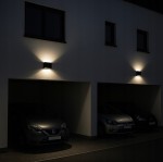 Kinkiet elewacyjny Gantio w kolorze czarnym, z dwoma diodami LED 6W, o temperaturze barwowej 4000K, zamontowany na ścianie, emitujący światło w górę i w dół, w kontekście oświetlenia garażu. Wodoodporny (IP44).
