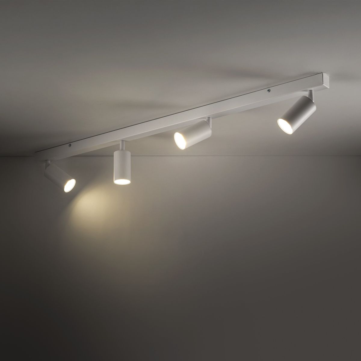 Lampa sufitowa Amis w kolorze białym, z czterema ruchomymi oprawkami na żarówki GU10. Ujęcie z góry, montowana na suficie, z minimalistycznym designem. Dwa reflektory włączone, oświetlające powierzchnię.