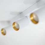 Lampa sufitowa Amis w białym kolorze z trzema punktami świetlnymi GU10. Ujęcie z bliska, pokazujące cylindryczny kształt i złote detale wewnątrz opraw. Montowana na suficie, minimalistyczny design, idealna do nowoczesnych wnętrz.