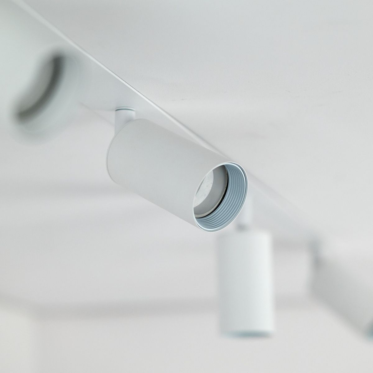 Lampa sufitowa podtynkowa Amis z czterema oprawami na żarówki GU10. Biała obudowa z metalu, okrągłe klosze w minimalistycznym stylu. Ujęcie z bliska, pokazujące detale mocowania i lampy.