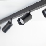 Lampa sufitowa Amis w kolorze czarnym, z czterema spotami na żarówki GU10. Ujęcie z boku, pokazujące jeden z reflektorów w matowym wykończeniu, zawieszony na prostokątnej podstawie. Tło białe, minimalistyczne.