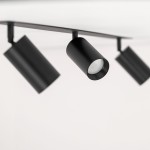 Lampa sufitowa podtynkowa Amis z trzema punktami świetlnymi typu GU10 w kolorze czarnym. Ujęcie z boku, ukazujące cylindryczne klosze zamocowane na metalowej listwie. Tło jasne, minimalistyczne.