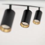 Lampa sufitowa Amis w kolorze czarnym, z trzema spotami na żarówki GU10. Ujęcie z bliska pokazuje cylindryczne klosze z złotymi detalami wewnętrznymi, zamontowane na prostokątnej podstawie.