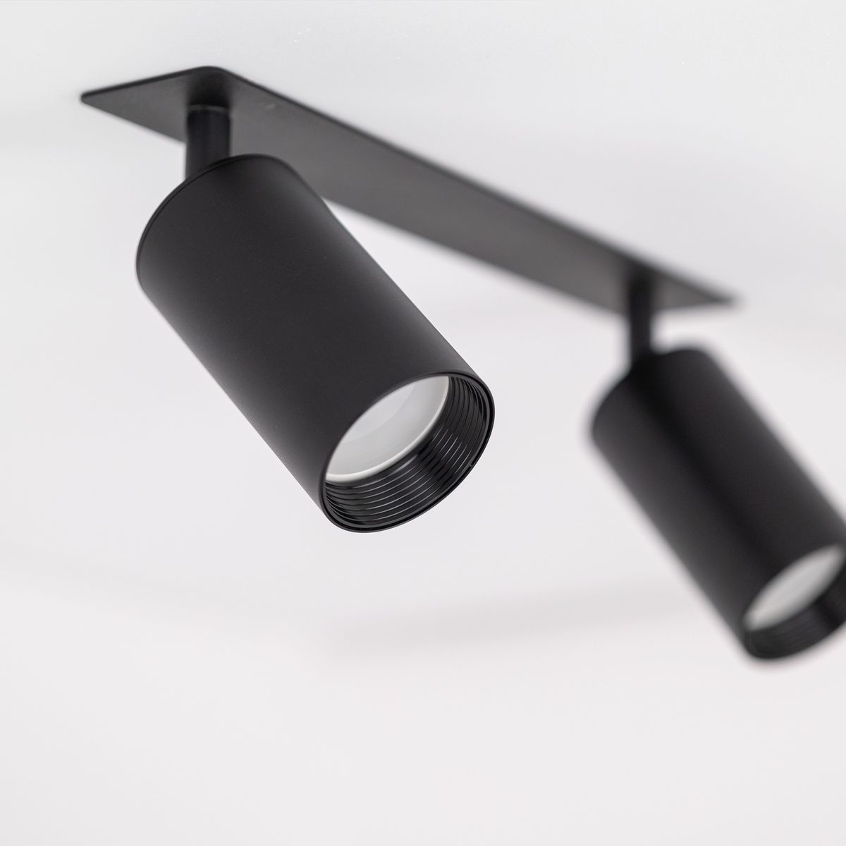 Lampa sufitowa podtynkowa Amis w kolorze czarnym z dwoma reflektorami GU10, zamontowana na prostokątnej podstawie. Reflektory mają cylindryczny kształt, umieszczone pod kątem, co umożliwia skierowanie światła w różnych kierunkach.