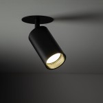 Lampa sufitowa podtynkowa Amis w kolorze czarnym, z cylindrycznym kloszem, montowana do sufitu. Widoczna żarówka GU10 emitująca światło, z widoczną fakturą w środku klosza. Ujęcie z boku, ukazujące detale konstrukcji.