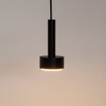 Lampa wisząca Stamp w kolorze czarnym z jedną oprawą GX53. Ma cylindryczny kształt z matowym wykończeniem. Zawieszona na cienkim przewodzie, emitująca ciepłe światło, idealna do nowoczesnych wnętrz.