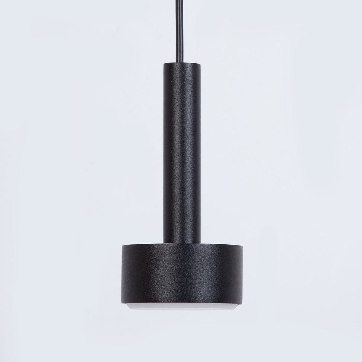 Lampa wisząca Stamp z dwoma gniazdami GX53 w kolorze czarnym. Okrągła podstawa z matowego metalu z cienkim, prostym uchwytem. Ujęcie frontalne, zawieszona na czarnym kablu, na jasnym tle.