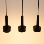 Lampa wisząca Stamp w kolorze czarnym z trzema okrągłymi kloszami. Produkt zawiera dwa gniazda G9 i trzy GX53. Ujęcie frontalne, z widocznymi detalami i cienkimi przewodami. Tło jasne, co podkreśla design lampy.