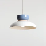 Lampa wisząca Aldo z białym kloszem i niebieską osłoną, z elementem drewnianym. Ujęcie frontalne, zawieszona na cienkim przewodzie. Kluczowe cechy to nowoczesny design i kolorystyka, idealna do nowoczesnych wnętrz.