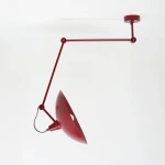 Lampa wisząca Melos 1xE27 w intensywnym czerwonym kolorze, z metalowym kloszem o półkolistym kształcie. Uchwyt i ramię w tej samej barwie, montowane do sufitu. Klosz z otworem, wiszący pod kątem, na białym tle.