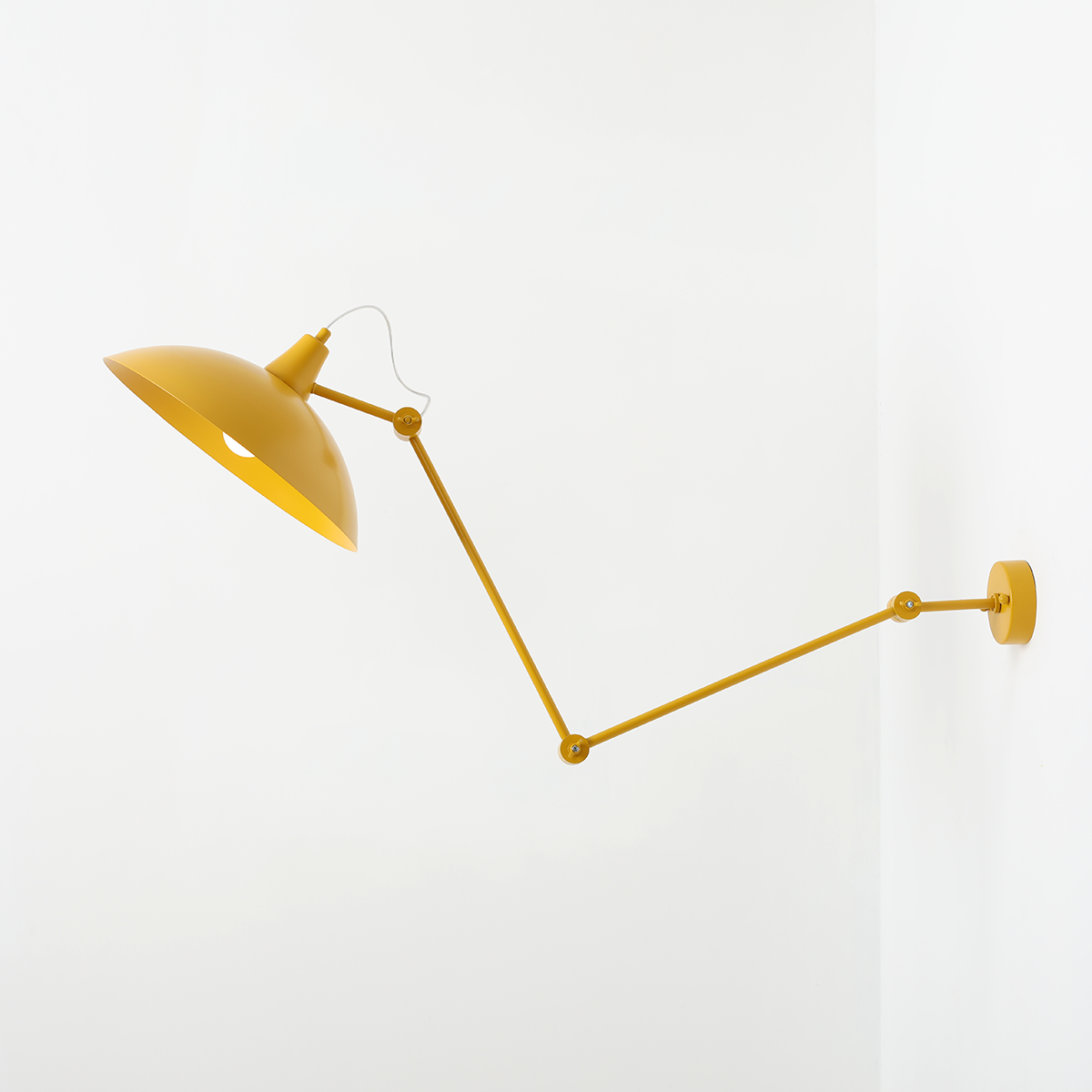 Lampa wisząca Melos 1xE27 w intensywnym żółtym kolorze, z metalowym kloszem w kształcie miski. Wydłużony, regulowany ramion o prostym designie, zamontowana na ścianie. Tło białe, co podkreśla kolor lampy.