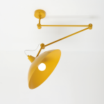 Lampa wisząca Melos z jedną oprawą E27 w kolorze żółtym. Posiada metalowy klosz w kształcie stożka oraz regulowany, przegubowy ramie. Zawieszona na suficie, na białym tle, z widocznym źródłem światła w środku klosza.