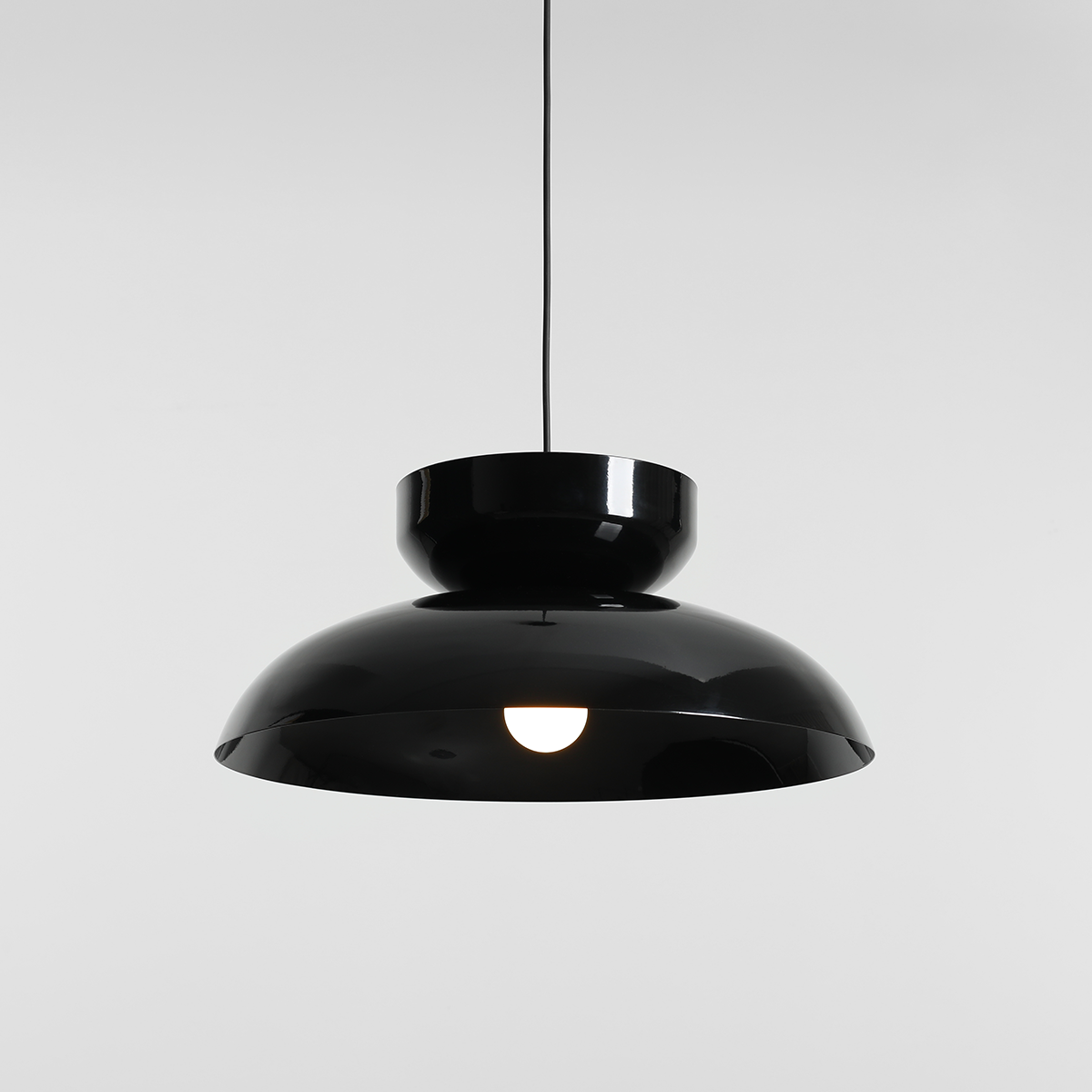 Lampa wisząca Aldo w kolorze czarnym, z metalowym kloszem o gładkiej, błyszczącej powierzchni. Posiada jedno miejsce na żarówkę E27. Ujęcie z dołu, pokazujące elegancki kształt i centralne źródło światła.