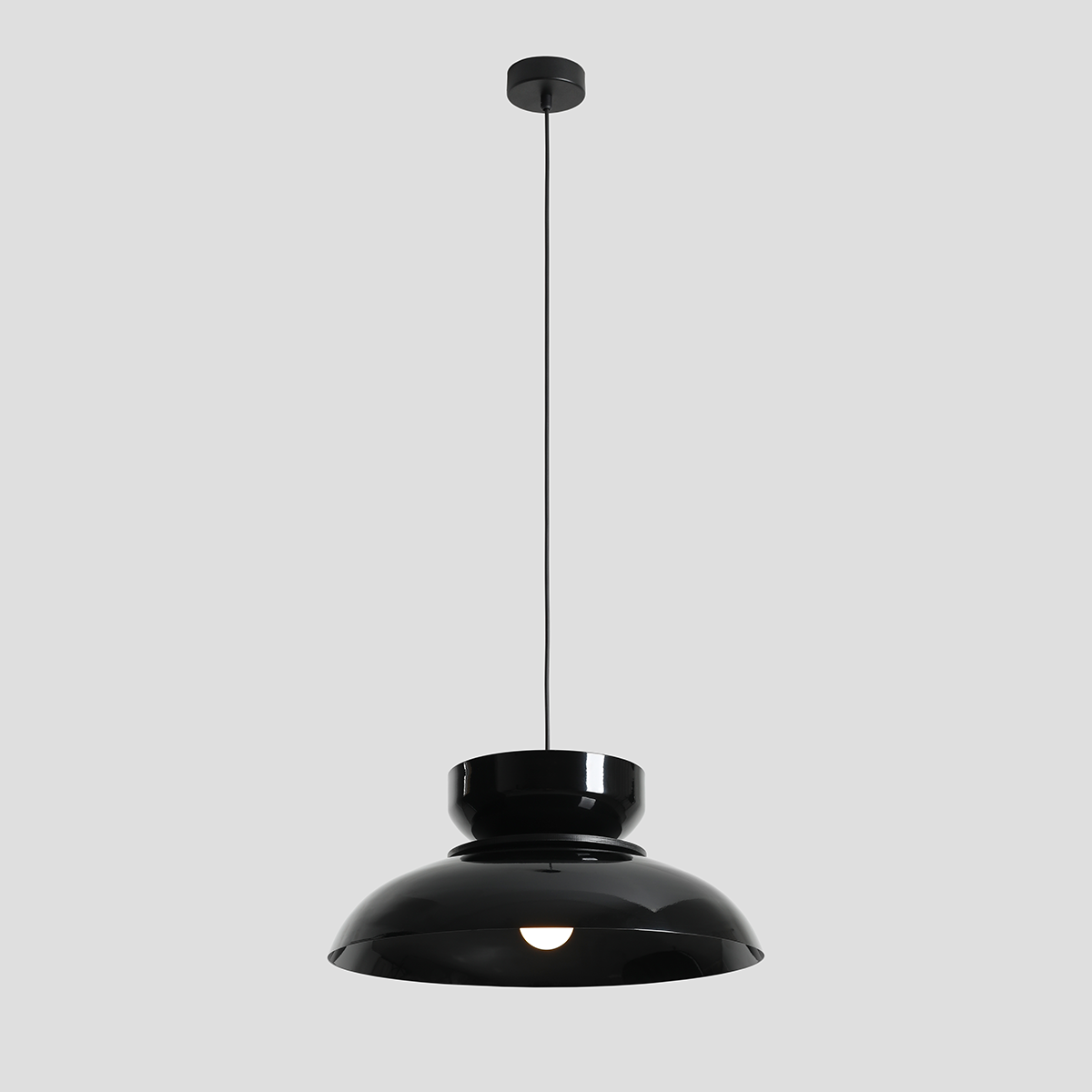 Czarna lampa wisząca Aldo z jednym gniazdem E27, o eleganckim, zaokrąglonym kształcie. Ujęcie frontalne, zawieszona na długim przewodzie, z połyskującą powierzchnią oraz subtelnym otworem na żarówkę. Tło jednolite, szare.