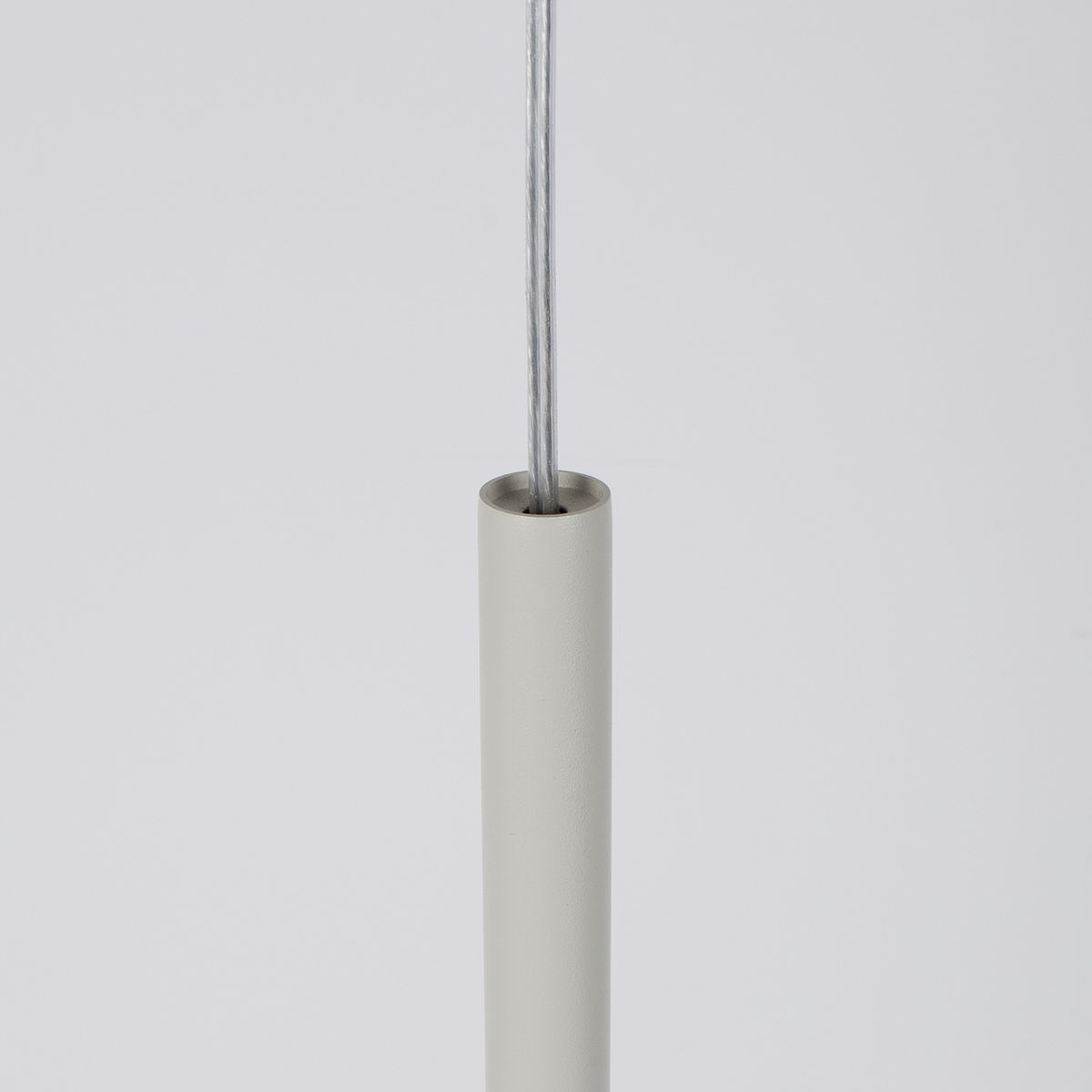 Lampa wisząca Sopel w kolorze szarym beżowym z oprawką na żarówkę G9. Ujęcie z dołu pokazuje gładki, cylindryczny element mocujący z metalowym kablem. Prosty, minimalistyczny design.