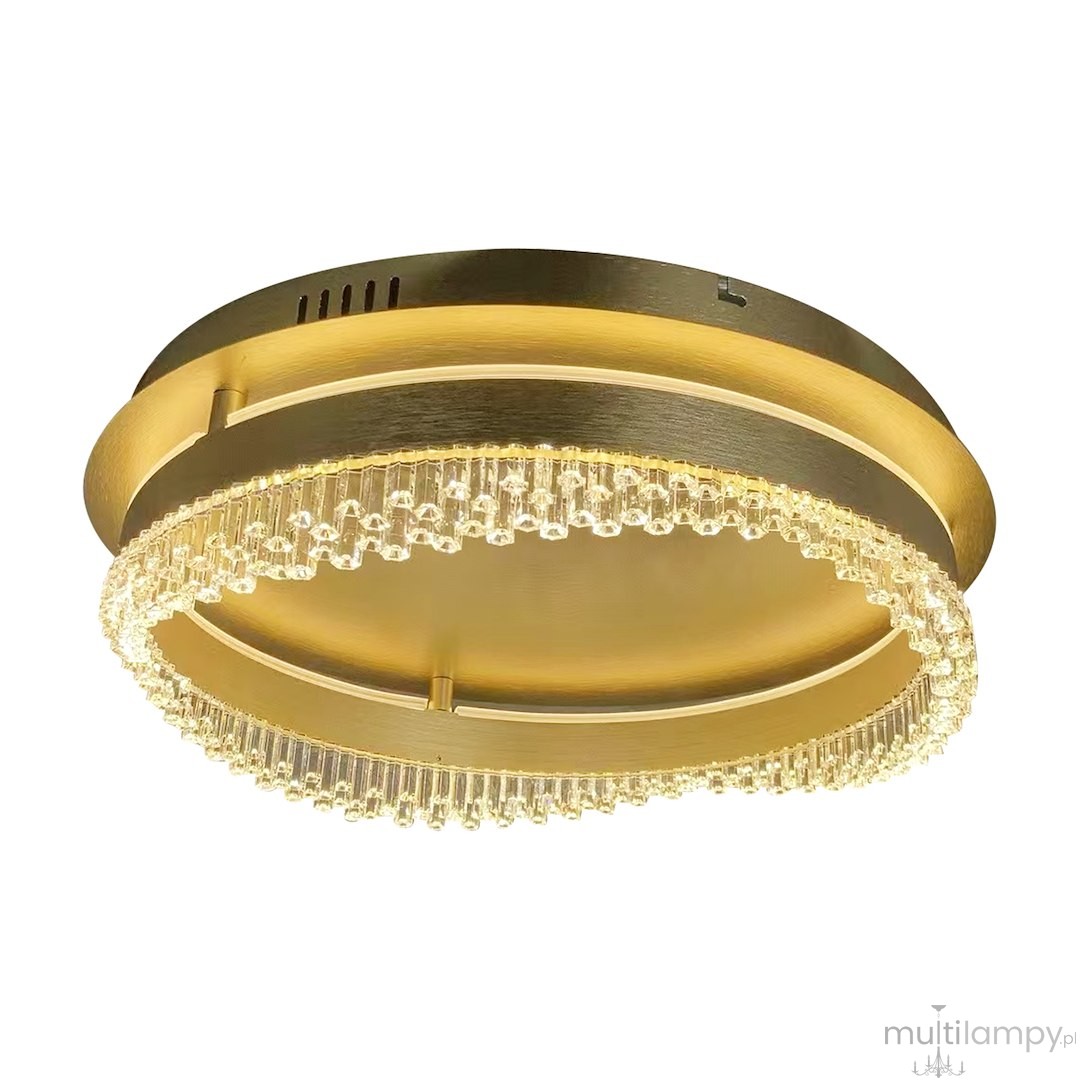 Lampa sufitowa LED Preciosa 36W o temperaturze barwowej 4000K, w złotym kolorze. Okrągła, z dekoracyjnym pierścieniem z przezroczystych elementów. Ujęcie z boku, ukazujące efektowne wykończenie oraz krawędź z kryształków.