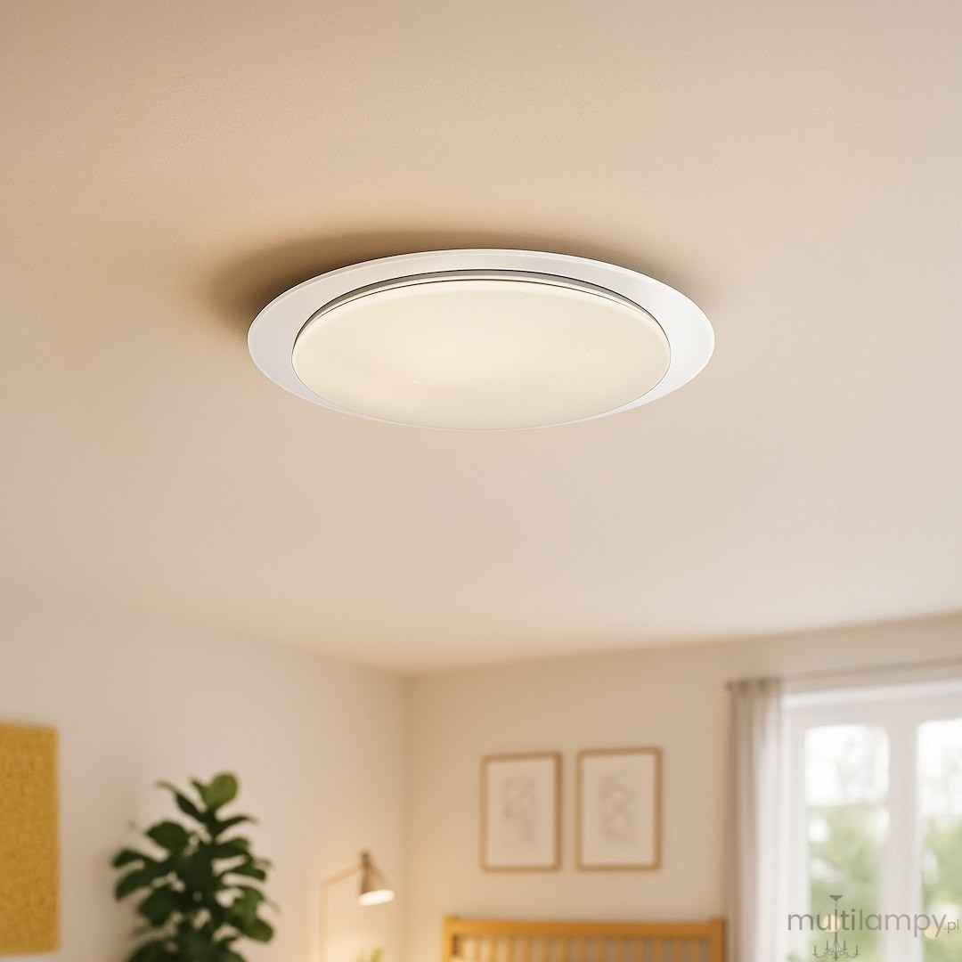 Plafon LED Sonic D85 o mocy 100W w kolorze białym, okrągły z matowym kloszem, montowany na suficie. Widoczny pilot do zdalnego sterowania. Tło w jasnych odcieniach z roślinnymi akcentami i elementami wystroju wnętrza.