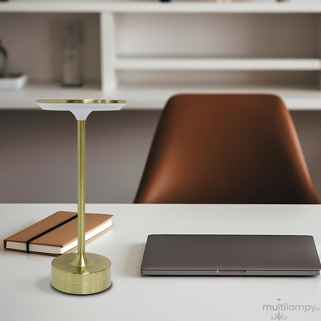 Lampa stołowa LED Tavolo 2,5W CCT w kolorze złotym, z okrągłą podstawą i smukłym stelażem. Ujęcie frontalne na biurku obok laptopa i notesu, na tle jasnej aranżacji wnętrza.