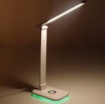 Biała lampka biurkowa Alma LED 12W/CCT z regulowanym ramieniem. U podstawy znajduje się kolorowy przycisk z podświetleniem RGB. Kąt ujęcia z boku, pokazujący nowoczesny design i funkcjonalność lampy.