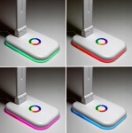 Biała lampka biurkowa Alma LED 12W/CCT z funkcją RGB. Widoczna podstawka z kolorowym podświetleniem (zielony, czerwony, różowy, niebieski) oraz okrągły przycisk sterujący. Kąt ujęcia z boku, ukazujący detale i różnorodność kolorów.