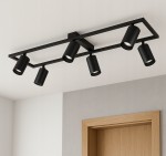 Lampa sufitowa Bumo z sześcioma reflektorami GU10 w kolorze czarnym, zamontowana na prostokątnej ramie. Reflektory skierowane w różnych kierunkach, umieszczone pod kątem. Tło w jasnych odcieniach z drewnianymi akcentami.
