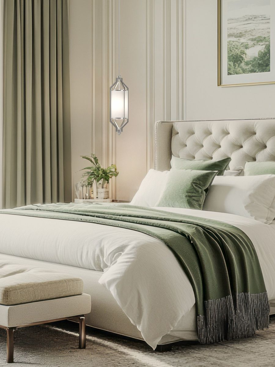 Lampa wisząca Zundo Satin Nikiel D20 w kolorze srebrnym z kloszem z mlecznego szkła, zawieszona nad łóżkiem w sypialni. Oświetlenie podkreśla elegancki wystrój wnętrza z miękkimi poduszkami i narzutą w zielonym odcieniu.