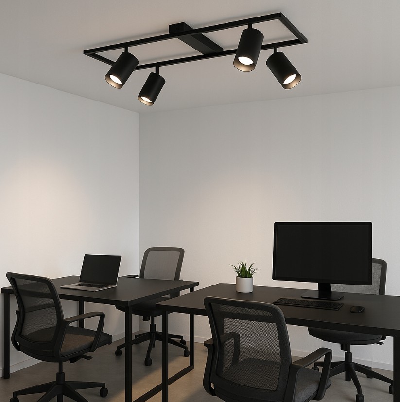 Czarna lampa sufitowa Bumo z czterema reflektorami GU10, zamontowana na prostokątnej podstawie. Reflektory są skierowane w różne strony, o cylindrycznym kształcie. Lampa znajduje się w nowoczesnym biurze z czarnymi biurkami i krzesłami.