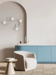 Kinkiet Boletta Parette Toupe IP44 w kolorze szarobeżowym, montowany na ścianie, z pojedynczym źródłem światła G9. Prosty, nowoczesny design z okrągłą oprawą, idealny do wnętrz. Widoczny w aranżacji z fotelem i stolikiem.