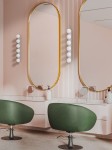 Lampa sufitowa Merino Parette w kolorze złotym, z miejscem na 6 żarówek G9, o nowoczesnym designie. Ujęcie frontalne, w aranżacji z lustrami i zielonymi fotelami w tle, na tle różowej ściany z pionowymi liniami.