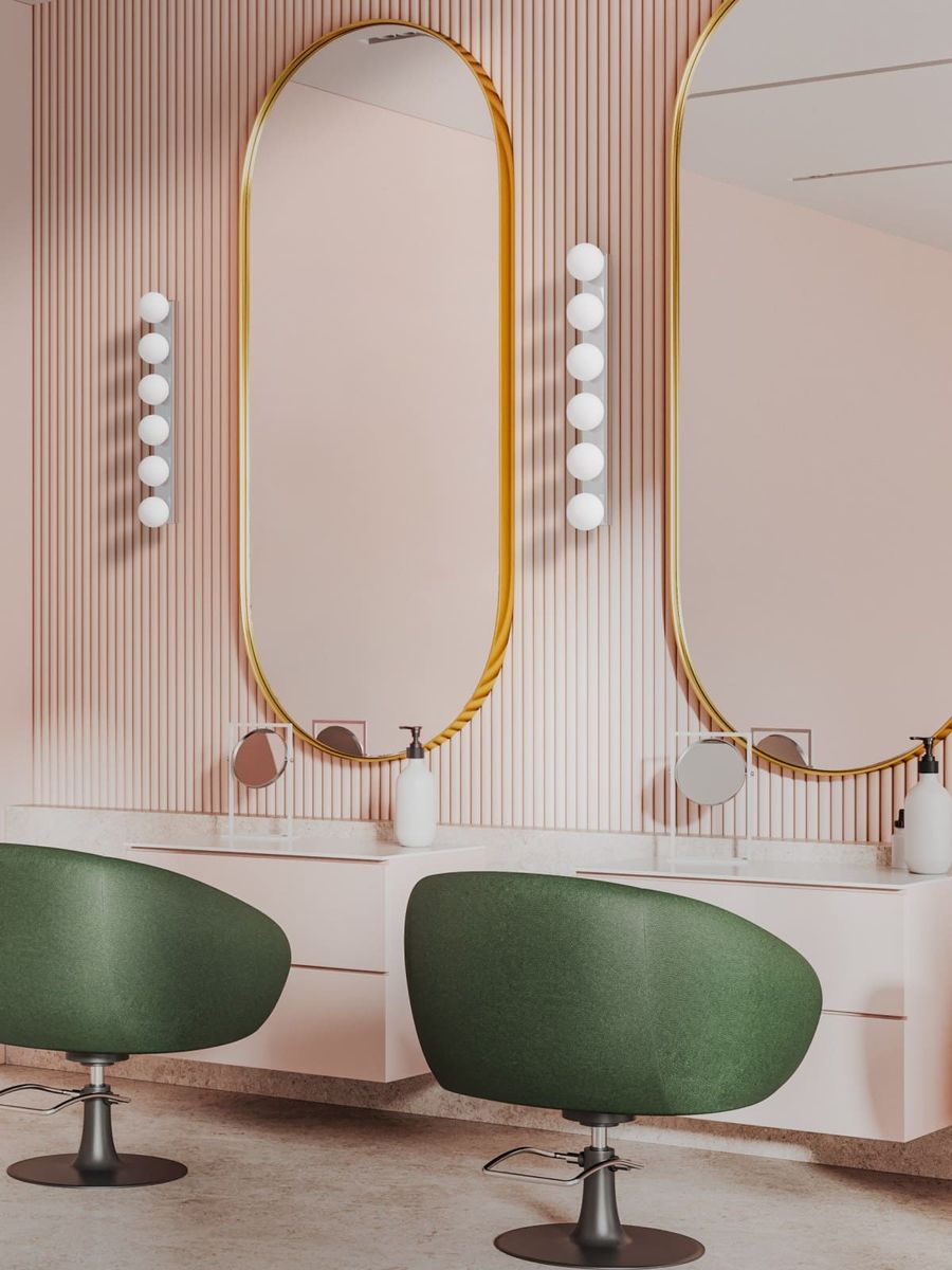 Lampa sufitowa Merino Parette Cromo 60 IP44 z sześcioma źródłami światła G9 w chromowanej obudowie, umieszczona w nowoczesnym wnętrzu z różowymi ścianami i zielonymi fotelami. Widoczne lustra i minimalistyczne akcesoria.