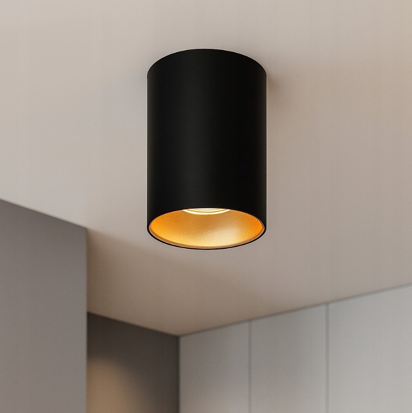 Lampa sufitowa tuba 1xGU10 w kolorze czarnym z wnętrzem w złotym odcieniu, zamontowana na suficie. Produkt o cylindrycznym kształcie, oświetlający przestrzeń z góry. Widoczny detal oprawy świetlnej.