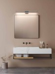 Luce Parette Nero 62 IP44 kinkiet LED 11W CCT w kolorze czarnym, zamontowany nad lustrem w łazience. Prosty, minimalistyczny design z metalowym mocowaniem, emitujący ciepłe światło, w otoczeniu nowoczesnej umywalki i dekoracji.