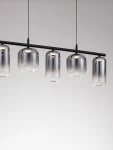 Lampa wisząca Anuco z pięcioma kloszami LED 19W, czarna. Klosze w kształcie cylindrów z przezroczystego szkła, zawieszone na cienkiej metalowej rurze. Ujęcie frontalne, na jednolitym tle.