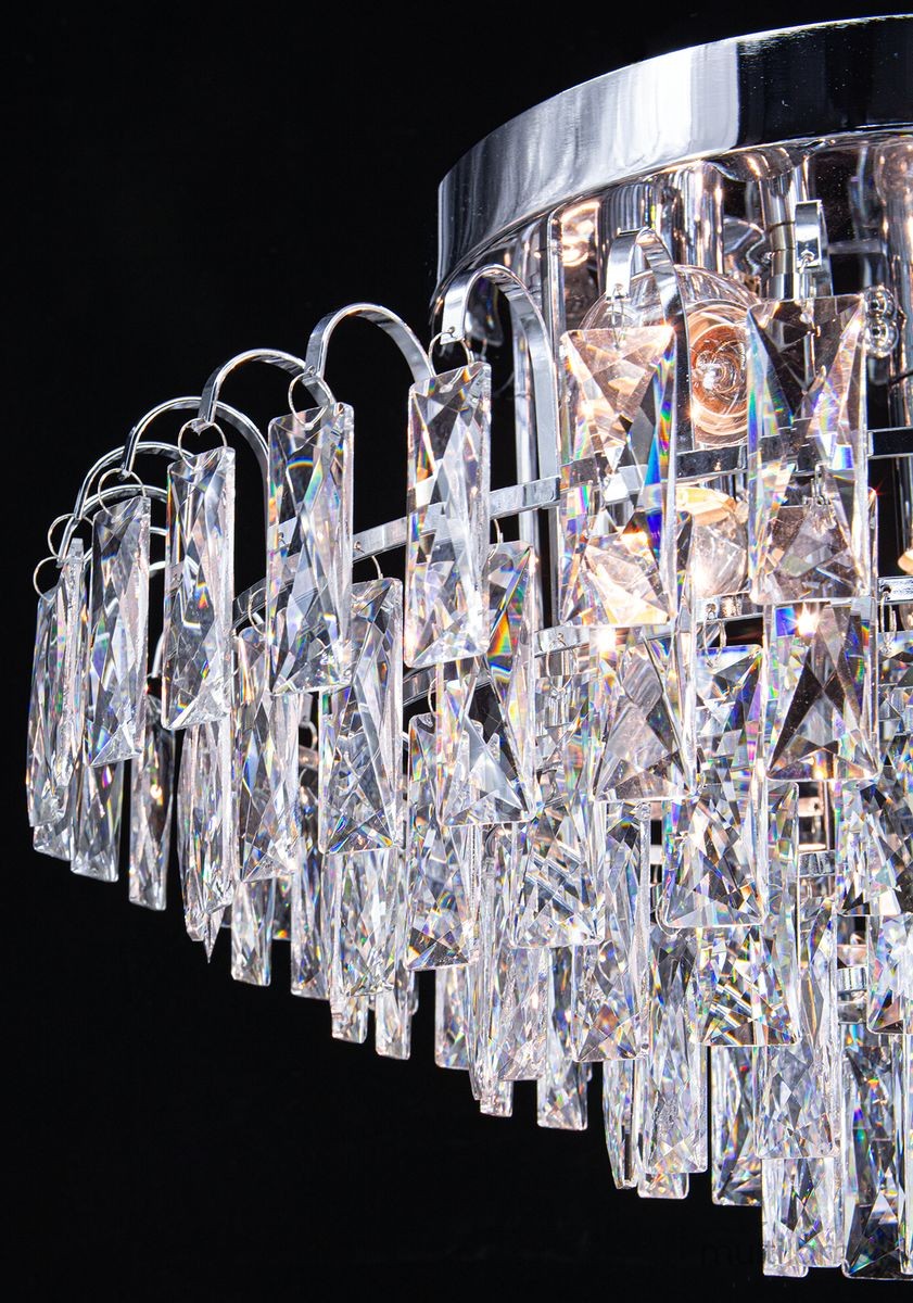 Lampa sufitowa Monaco 6xE27 w kolorze chromu, z kryształowymi elementami w kształcie prostokątów i trójkątów, zawieszona na metalowym stelażu. Ujęcie z dołu, ukazujące szczegóły kryształów i źródeł światła.