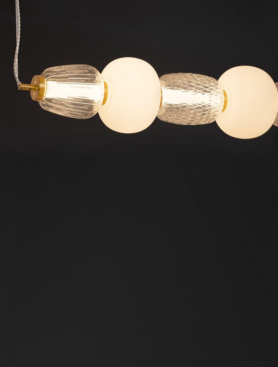 Złota lampa wisząca Arroyos z jednym źródłem LED 42W, składająca się z trzech kulistych kloszy: dwóch matowych białych i jednego przezroczystego, z fakturą. Ujęcie z góry, na jednolitym ciemnym tle, z widocznym kablem.