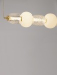Lampa wisząca Arroyos z jednym źródłem LED o mocy 42W, złożona z trzech kulistych elementów: dwóch szklanych o fakturze oraz jednego matowego, w kolorze złotym, zawieszona na cienkim przewodzie. Tło szare.