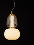 Lampa wisząca Arroyos z jednym źródłem LED 18W. Składa się z przezroczystego klosza o żłobionej fakturze i dolnej, matowej białej części. Zawieszona na cienkim, metalowym przewodzie, z złotymi akcentami. Tło czarne, co podkreśla elegancki design.