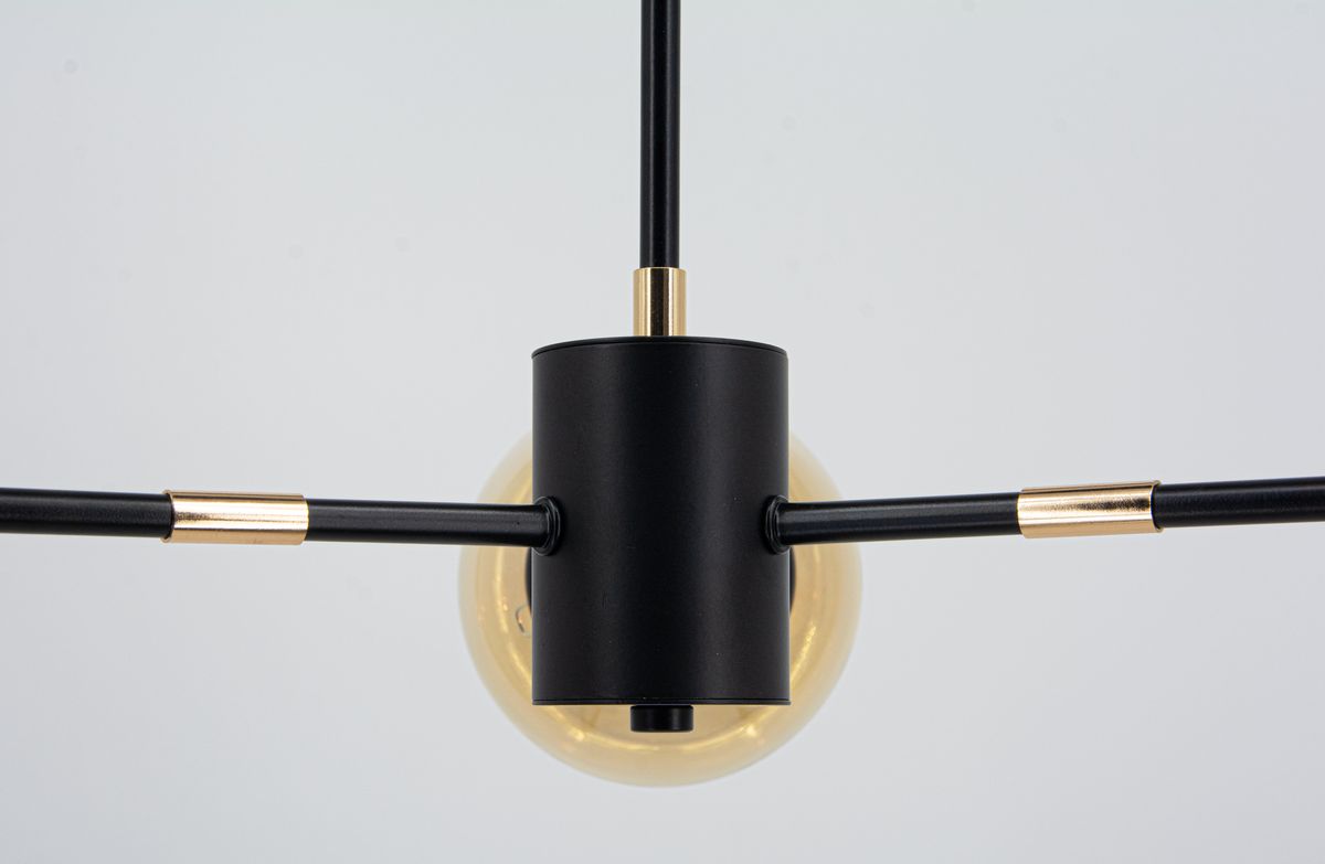 Lampa wisząca Gaja w kolorze czarnym i złotym, z trzema oprawami E27. Ujęcie z góry, pokazujące centralny element z czarnego metalu oraz złote akcenty. W tle widoczna przezroczysta kula żarówki. Produkt montowany, idealny do nowoczesnych wnętrz.