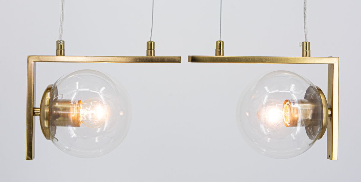 Lampa wisząca Brava 2xE27 w kolorze mosiądzu, z dwiema szklanymi kulami. Ujęcie frontalne, zawieszona na przezroczystych linkach. Widoczne złote detale oraz żarówki wewnątrz kul. Minimalistyczny design, idealna do nowoczesnych wnętrz.