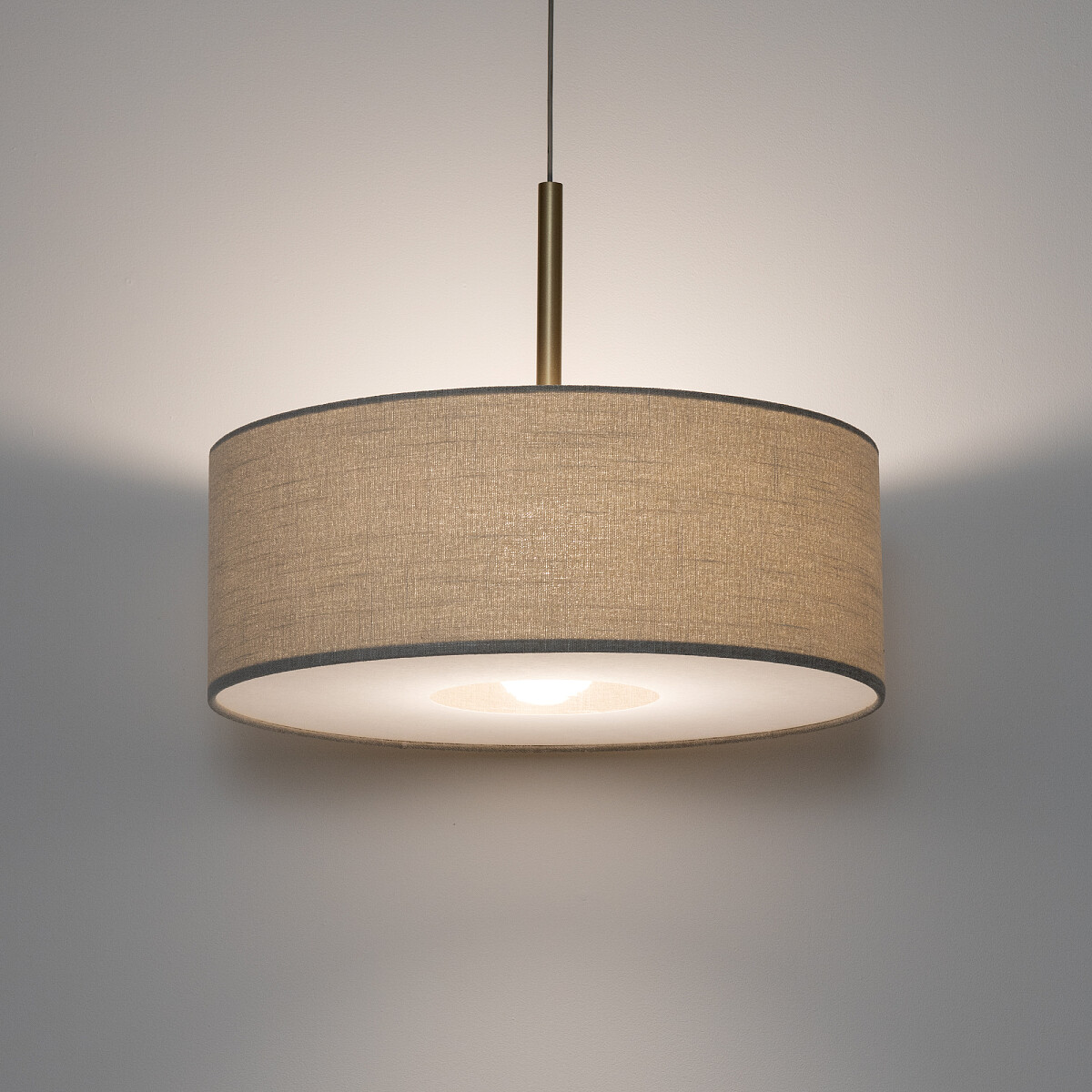 Lampa wisząca Santana M w kolorze kremowym, z okrągłym abażurem z tkaniny. Ujęcie z góry, lampa zawieszona na cienkim przewodzie. Widoczna oprawka E27 w centralnej części, delikatne oświetlenie tworzy przytulną atmosferę.