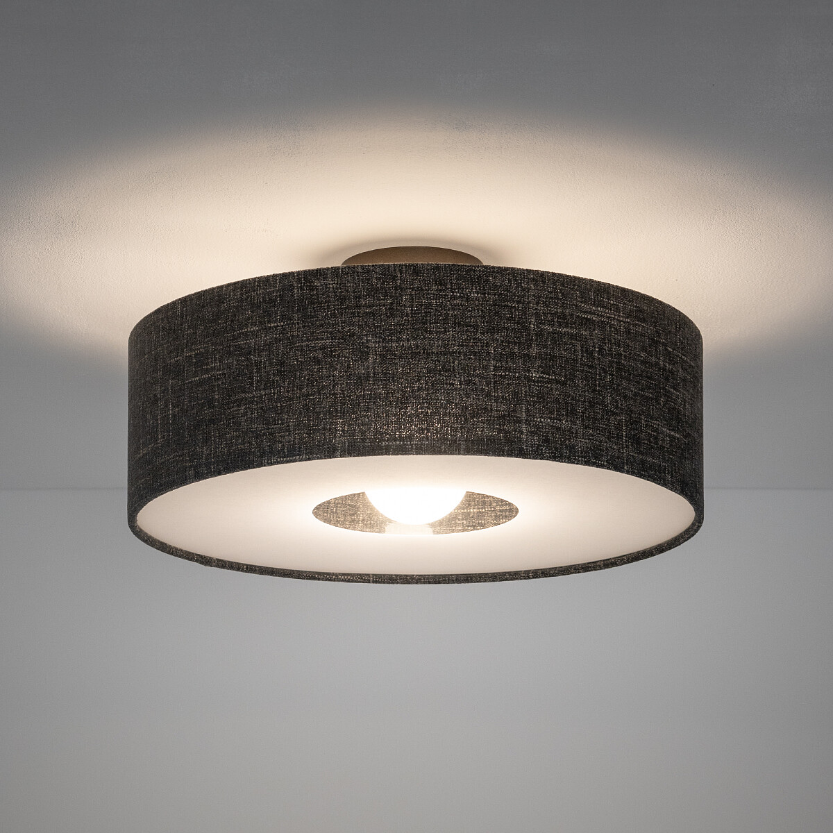 Lampa sufitowa Amarela M w czarnym melanżu, z okrągłym kloszem, z widoczną żarówką E27. Ujęcie frontalne, montowana do sufitu, z jasnym otoczeniem. Tekstura klosza przypomina materiał, co nadaje jej elegancki wygląd.